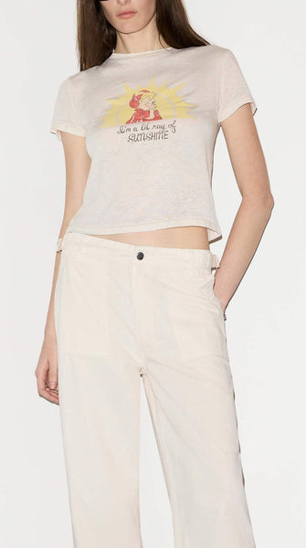 Woman wearing a white t-shirt with a graphic design and beige pants on a white background