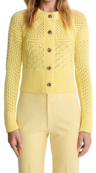 Woman wearing a yellow knit cardigan and pants on a white background