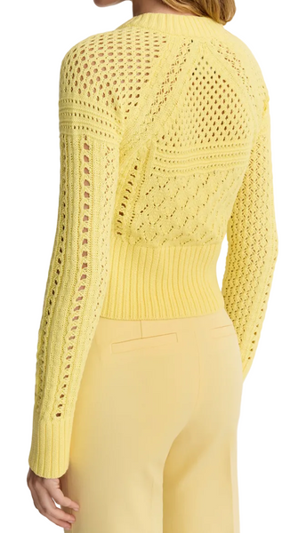 Woman wearing a yellow knitted top and pants on a white background