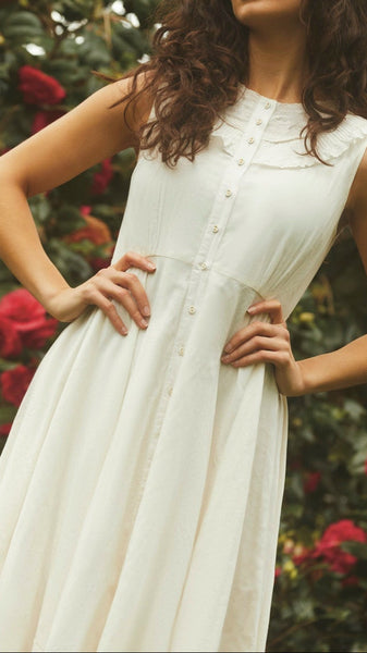 Woman in a white dress standing in front of a floral background