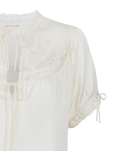 White blouse with lace details and drawstrings on a white background