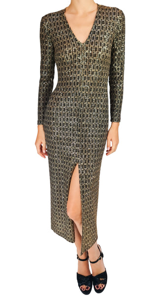A long-sleeve V-neck maxi dress with a geometric gold and black pattern, featuring a thigh-high front slit, modeled on a white background.