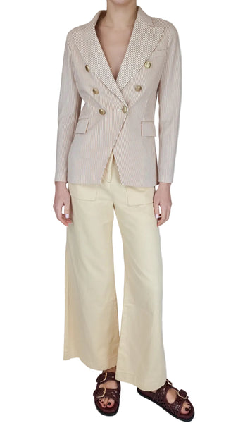 Person wearing a beige blazer and light-colored pants on a plain background