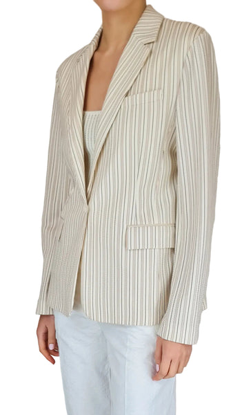 Person wearing a striped blazer and white pants against a plain background