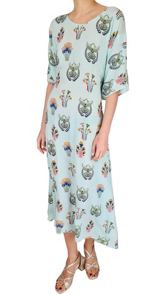 Woman wearing a light blue dress with owl pattern on a white background