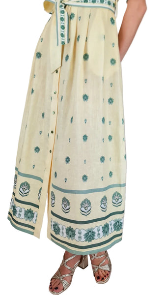 Long cream-colored dress with green floral patterns on a plain background
