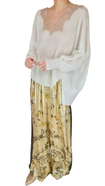Person wearing a white long-sleeve top and patterned yellow pants on a plain background
