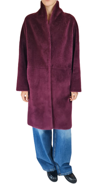 A person wearing a plush, long-sleeved shawl collar coat in deep plum purple, paired with wide-leg blue jeans and black shoes, shown against a plain white background.