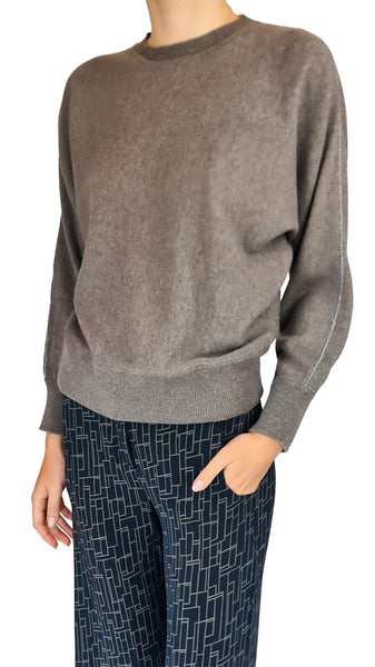 A person wearing a taupe-brown knit crewneck sweater and navy blue patterned trousers, shown from the neck down against a plain white background.