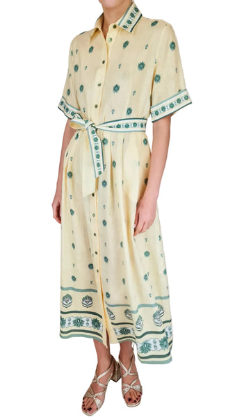 Woman wearing a long, light-colored dress with green patterns on a white background