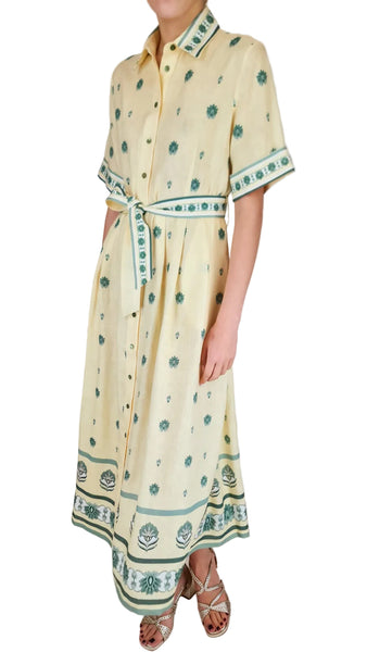 Person wearing a yellow dress with green patterns on a white background