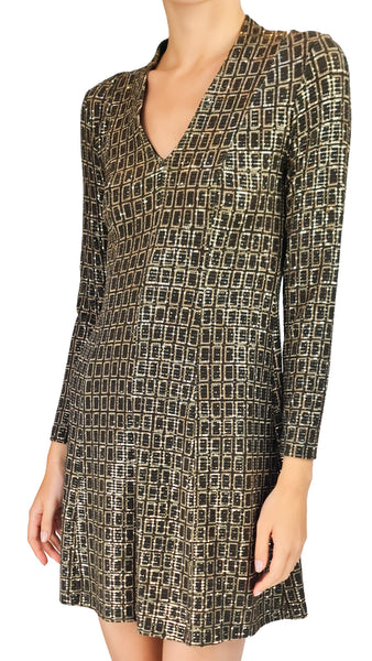 A woman wearing a long-sleeve V-neck mini dress with a metallic gold and black geometric grid pattern, shown against a plain white background.