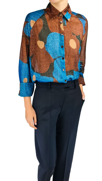 A model wearing a long-sleeve button-up shirt with an abstract organic pattern in blue, brown, and beige, paired with dark navy trousers, shown against a plain white background.