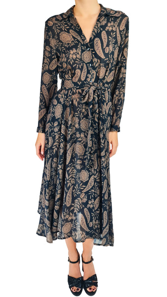 A woman modeling a long-sleeve midi dress with a soft black base and an intricate beige paisley and floral pattern. The dress features a V-neckline, a self-tie waist, and a flowy skirt, paired with black strappy high-heeled sandals against a plain white background.