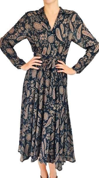 A woman modeling a long-sleeve midi wrap dress with a soft black base and an all-over beige paisley and floral pattern, set against a plain white background.