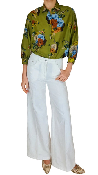 Person wearing a floral shirt and white pants on a plain background