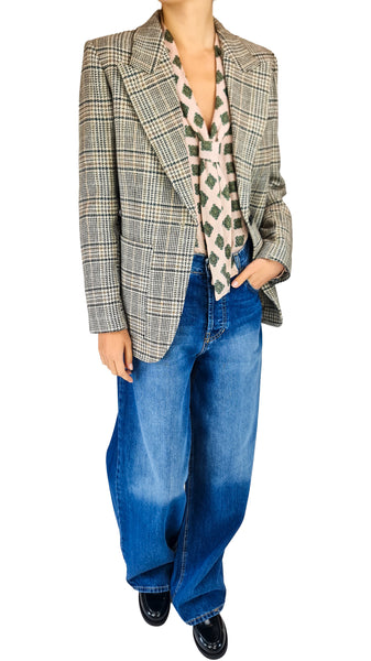 A model wearing a gray and beige plaid blazer over a patterned cream shirt, paired with wide-leg blue jeans and black shoes, shown against a plain white background.