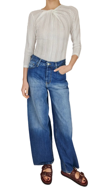 Person wearing a striped shirt and blue jeans against a neutral background
