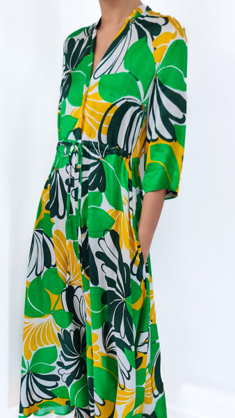 This dress features a bold and vibrant flower print in shades of green, white, and yellow. Stand out from the crowd and make a statement with this unique and eye-catching piece. Perfect for any summer occasion, this dress will bring a touch of tropical magic to your style.