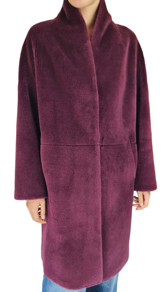 A person wearing a plush, fuzzy wrap coat in a deep plum purple color, paired with blue jeans, shown against a plain white background.
