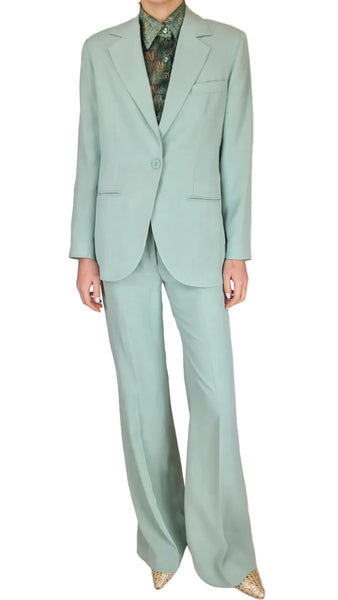 Person wearing a light green suit with a plain background
