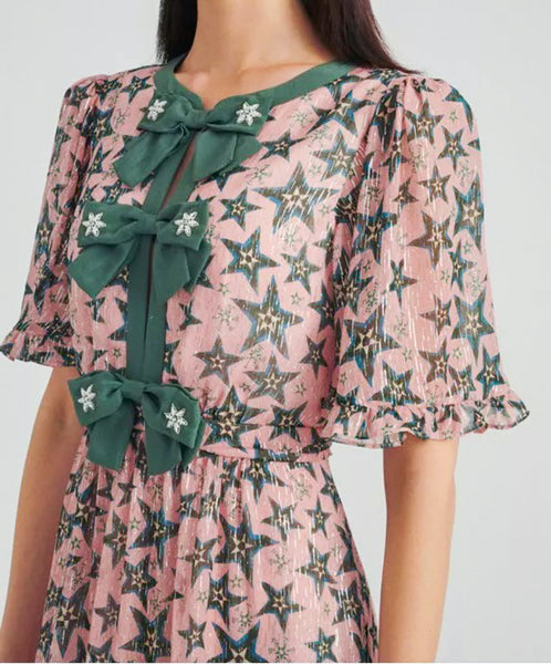 This gorgeous Saloni statement dress in pink and green star print features short bell sleeves, a keyhole opening front, and a trio of statement-making embroidered bows up the center front. Crafted in a silk georgette to the ankle length, pair it with minimal accessories and heels.